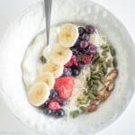 Greek yogurt in a bowl with fruit, nuts and seeds.