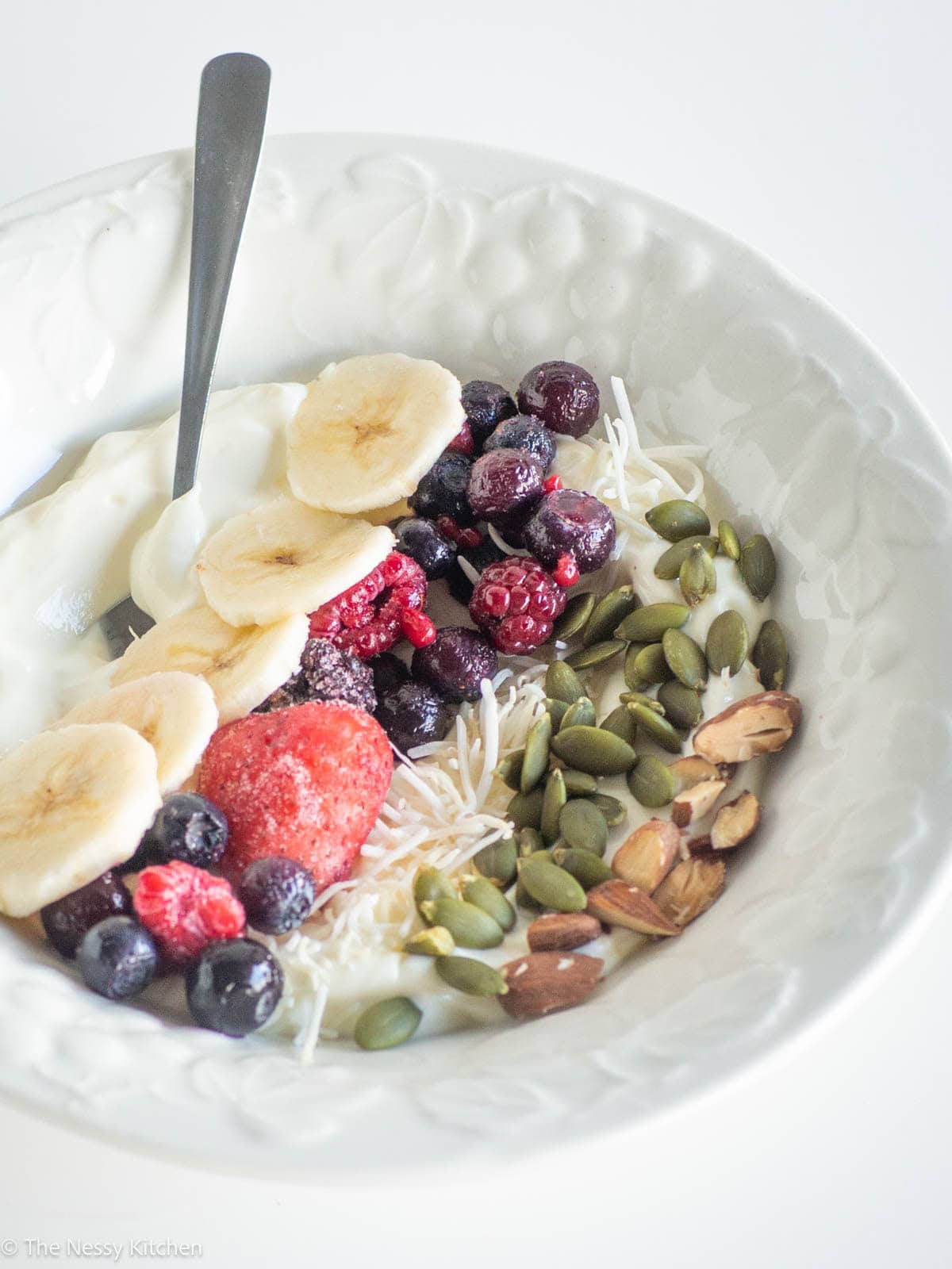 Yogurt in a bowl with fruit, nuts and seeds.