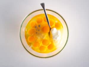 Eggs and yogurt whisked together in a bowl.