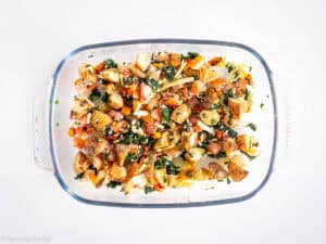 Vegetables scattered in the bottom of a casserole dish.