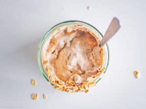 Oats mixed into a jar with yogurt and nut butter.