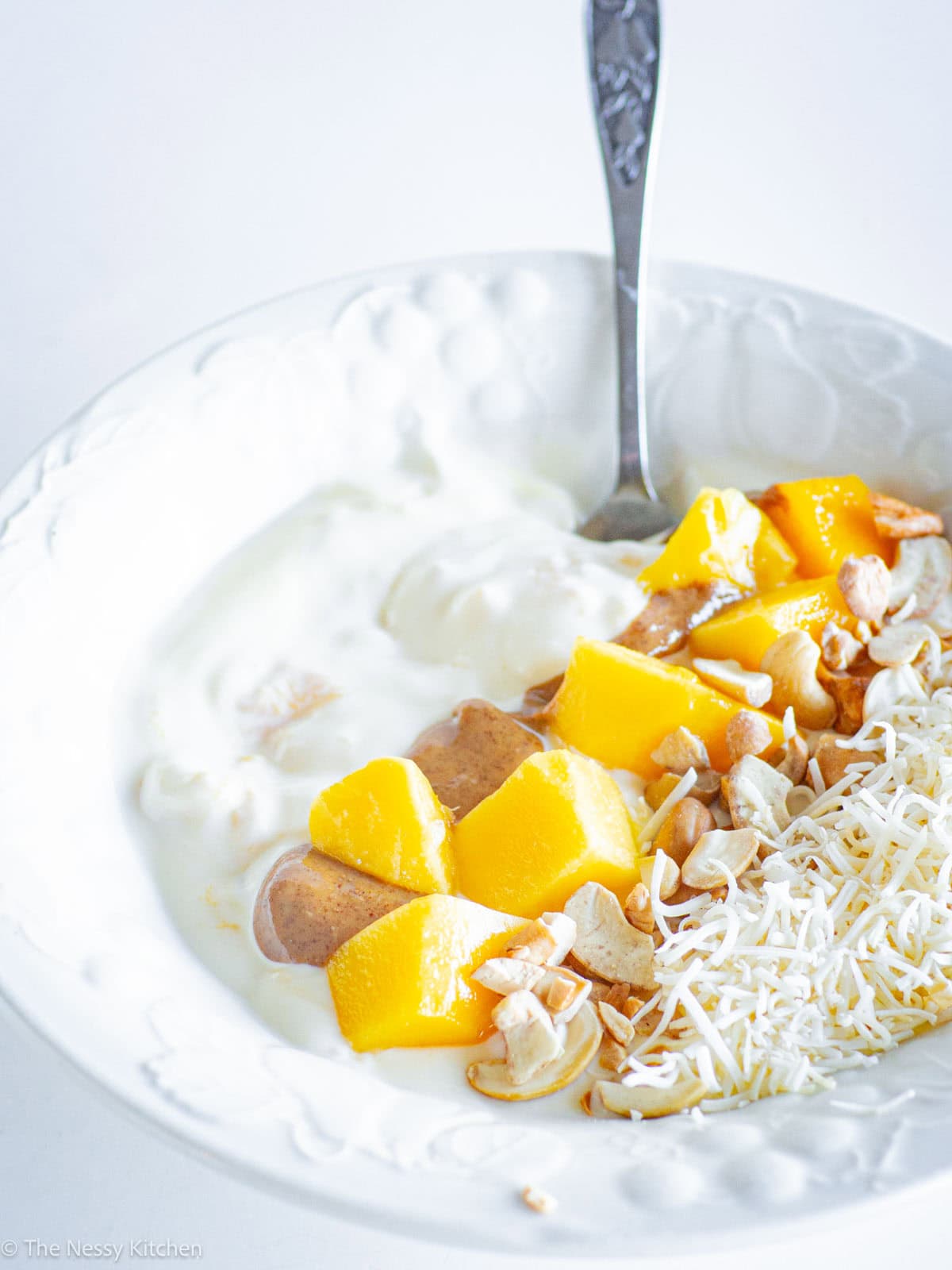 Mango yogurt bowl topped with coconut and nuts.