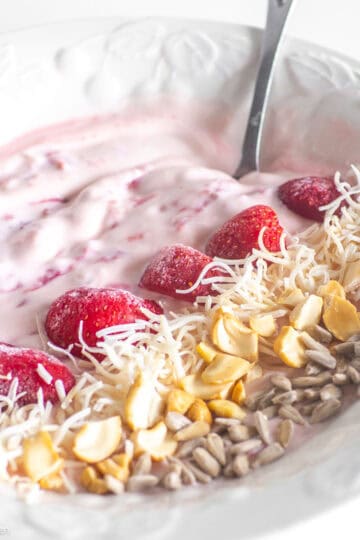 Yogurt bowl topped with strawberries and nuts.