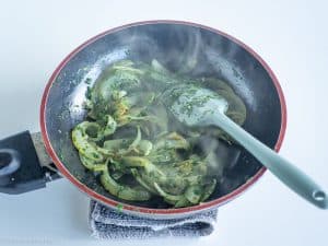 Onions and spinach cooked in a skillet.
