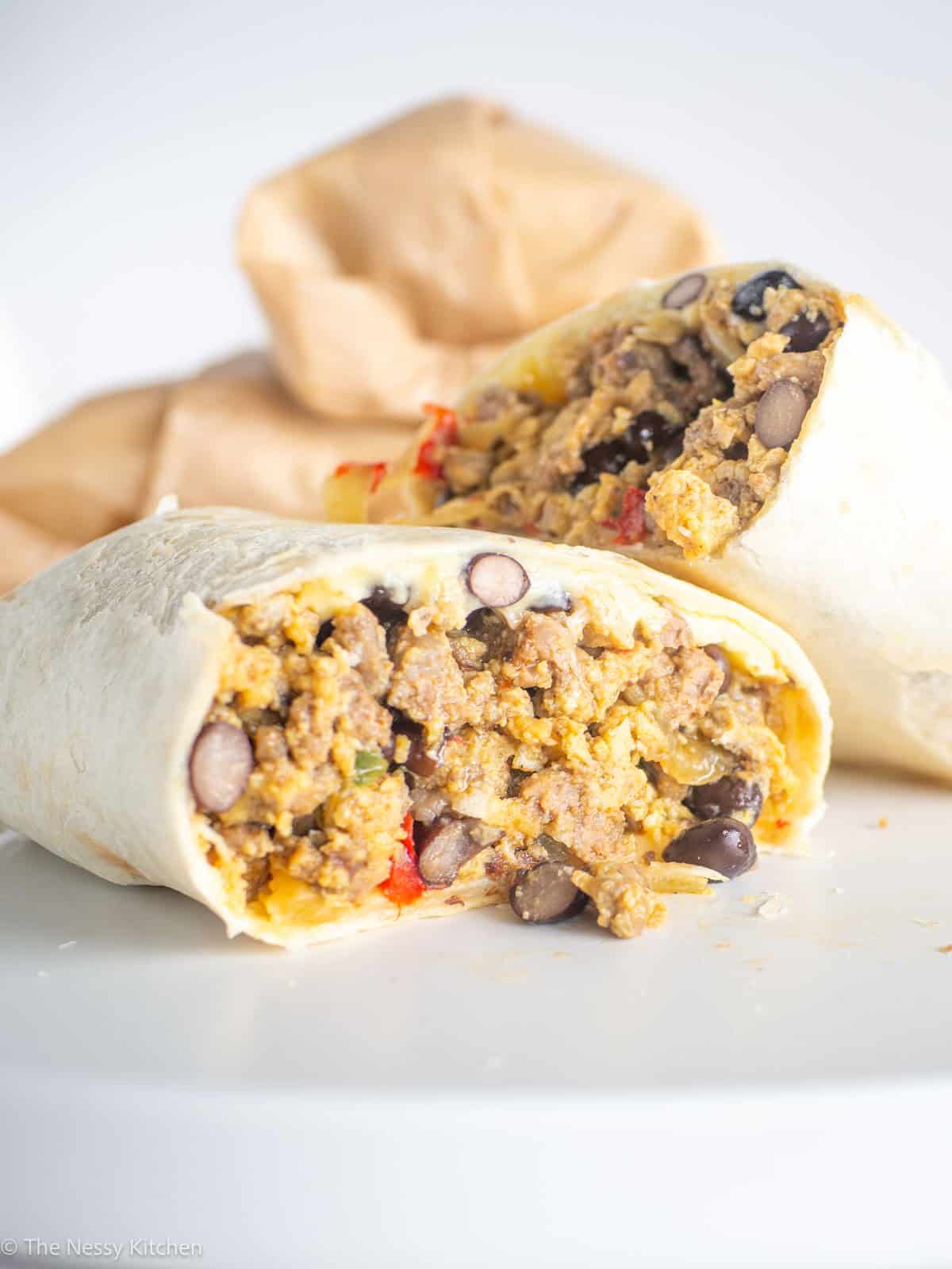 Breakfast burrito cut in half on plate.