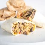 Breakfast burrito cut in half on plate.