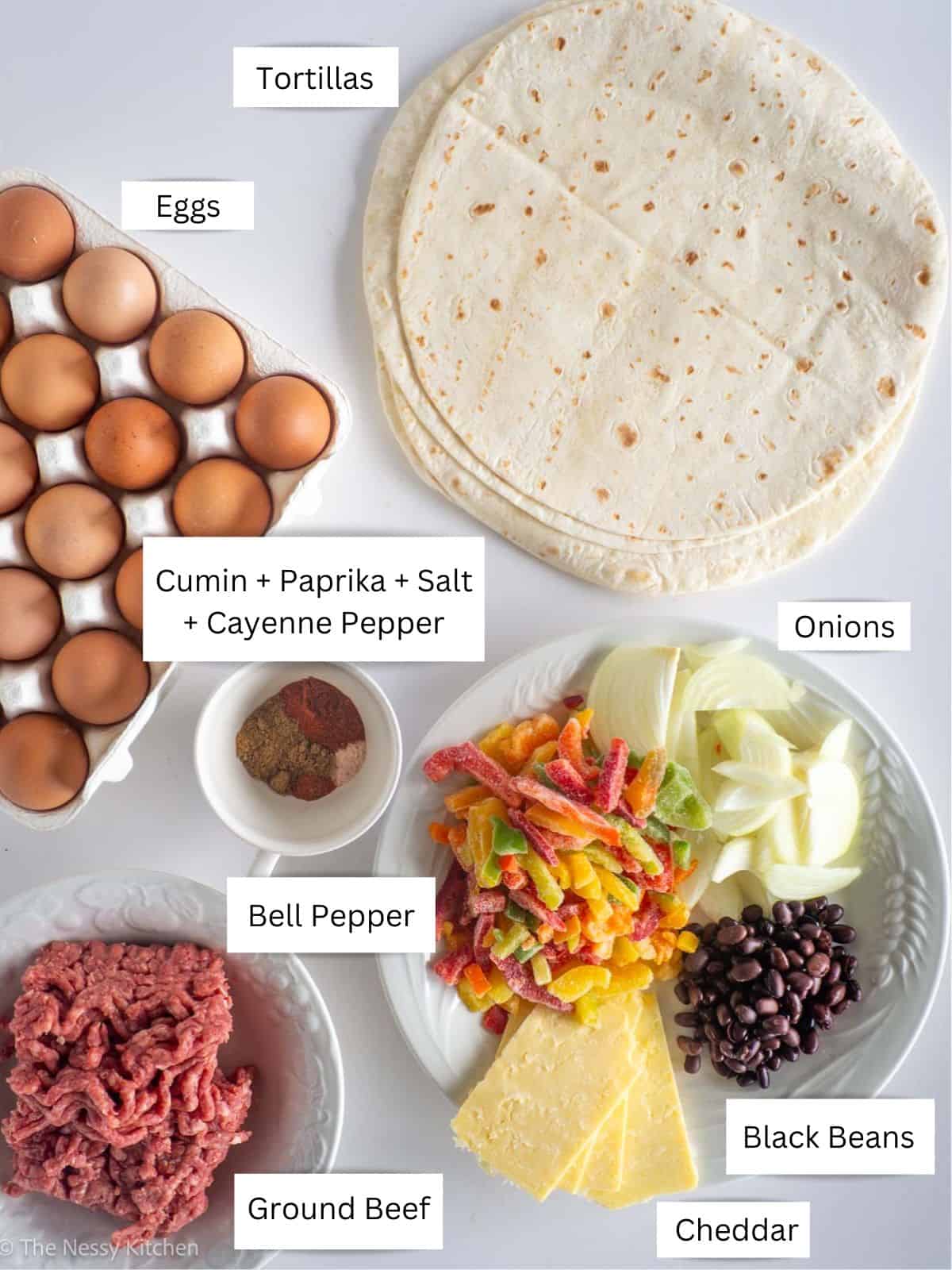 Breakfast burrito with ground beef ingredients laid out on counter.