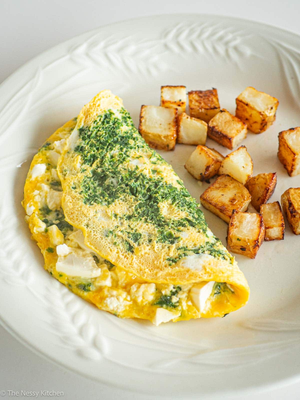 Feta Spinach Omelet with potatoes on a plate.