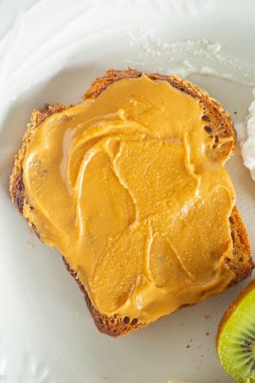 Peanut butter honey toast on plate with kiwi and cottage cheese.