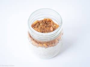 Jar of oatmeal topped with apple.