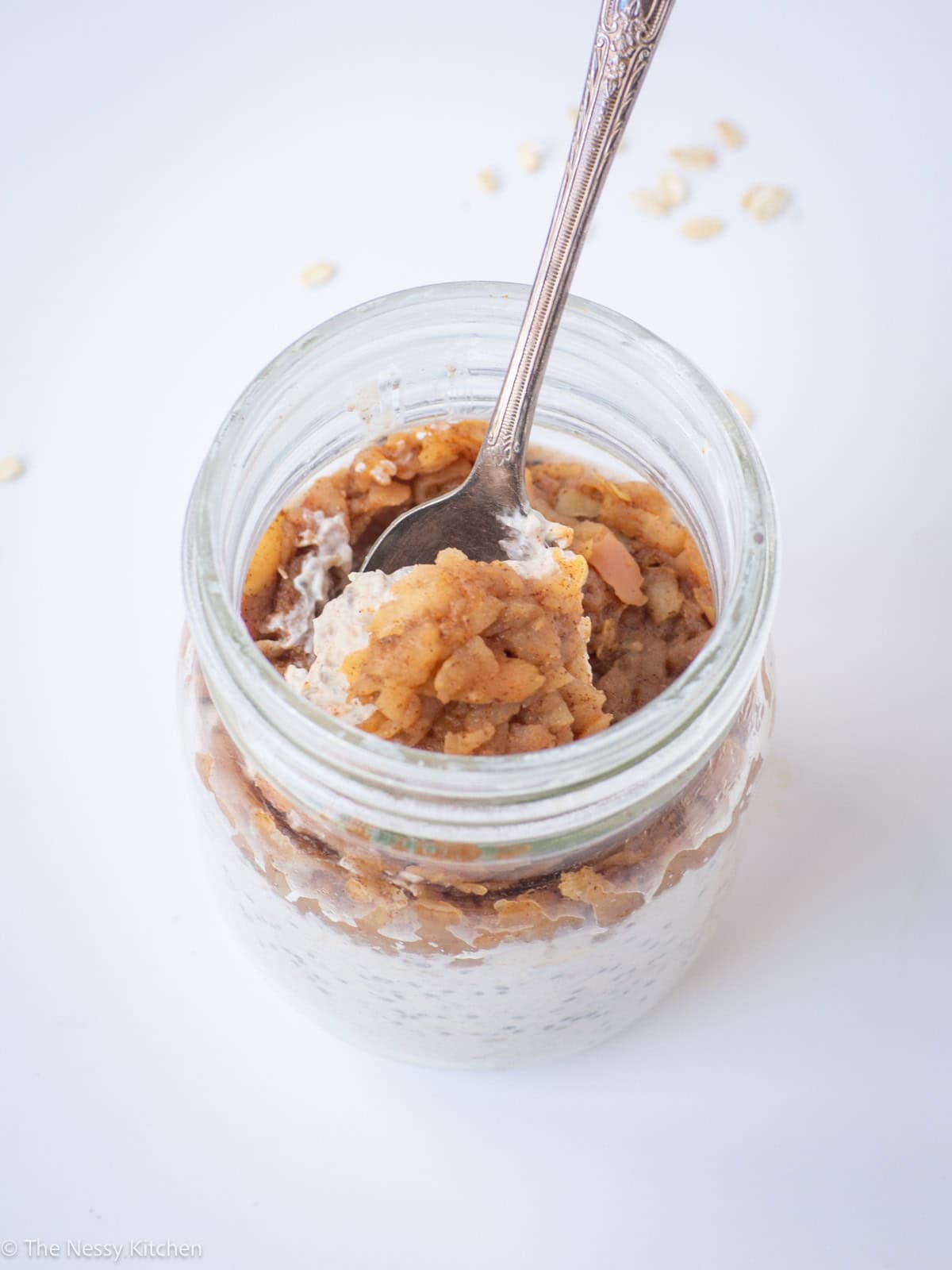 Jar of apple pie overnight oatmeal with a spoon.
