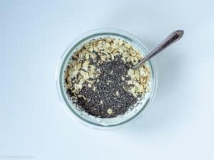 Oats and chia seeds added to glass jar.
