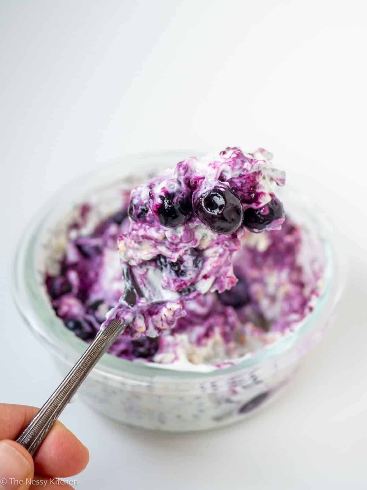 Blueberry overnight oats in glass jar with spoonful.