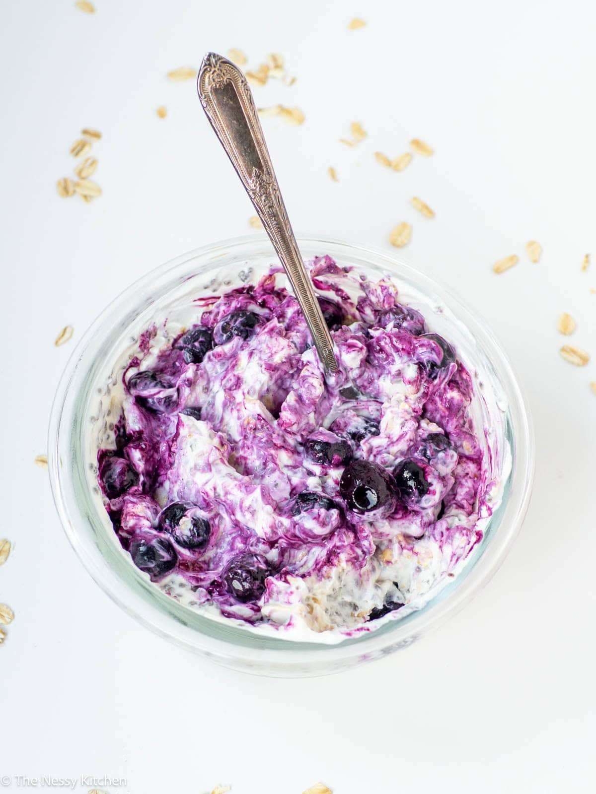 Blueberry overnight oats in glass jar on counter with spoon.