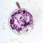Blueberry overnight oats in glass container with spoon.
