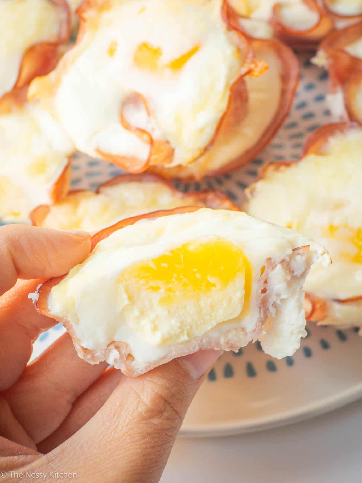 Hand holding a baked egg cup sliced in half.