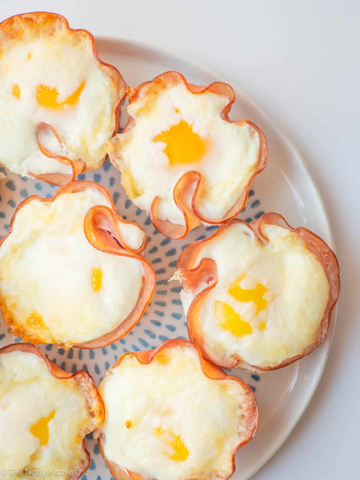 Eggs baked in ham with cheese on a plate.