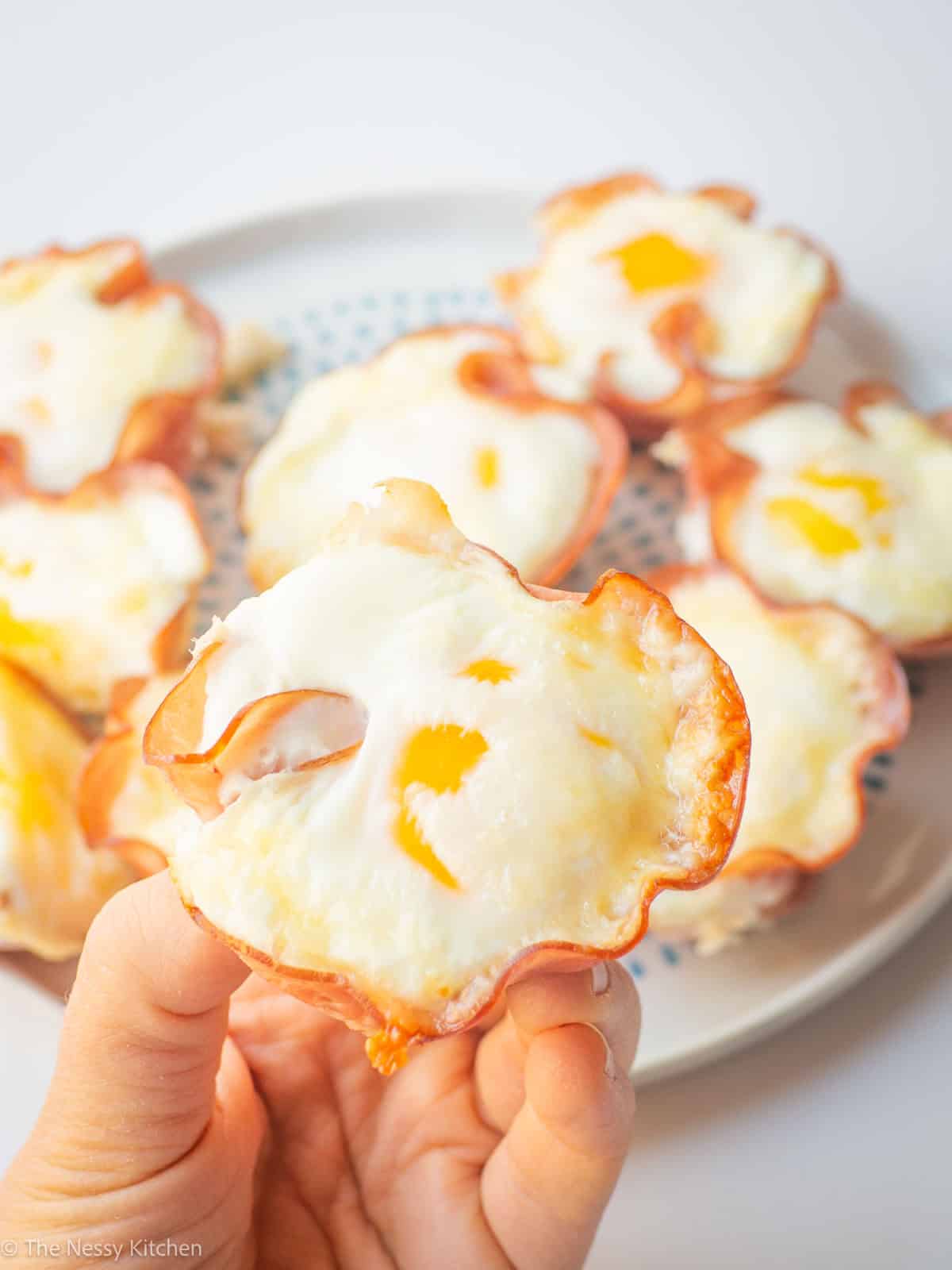 Hand grabbing an egg cup from a plate.