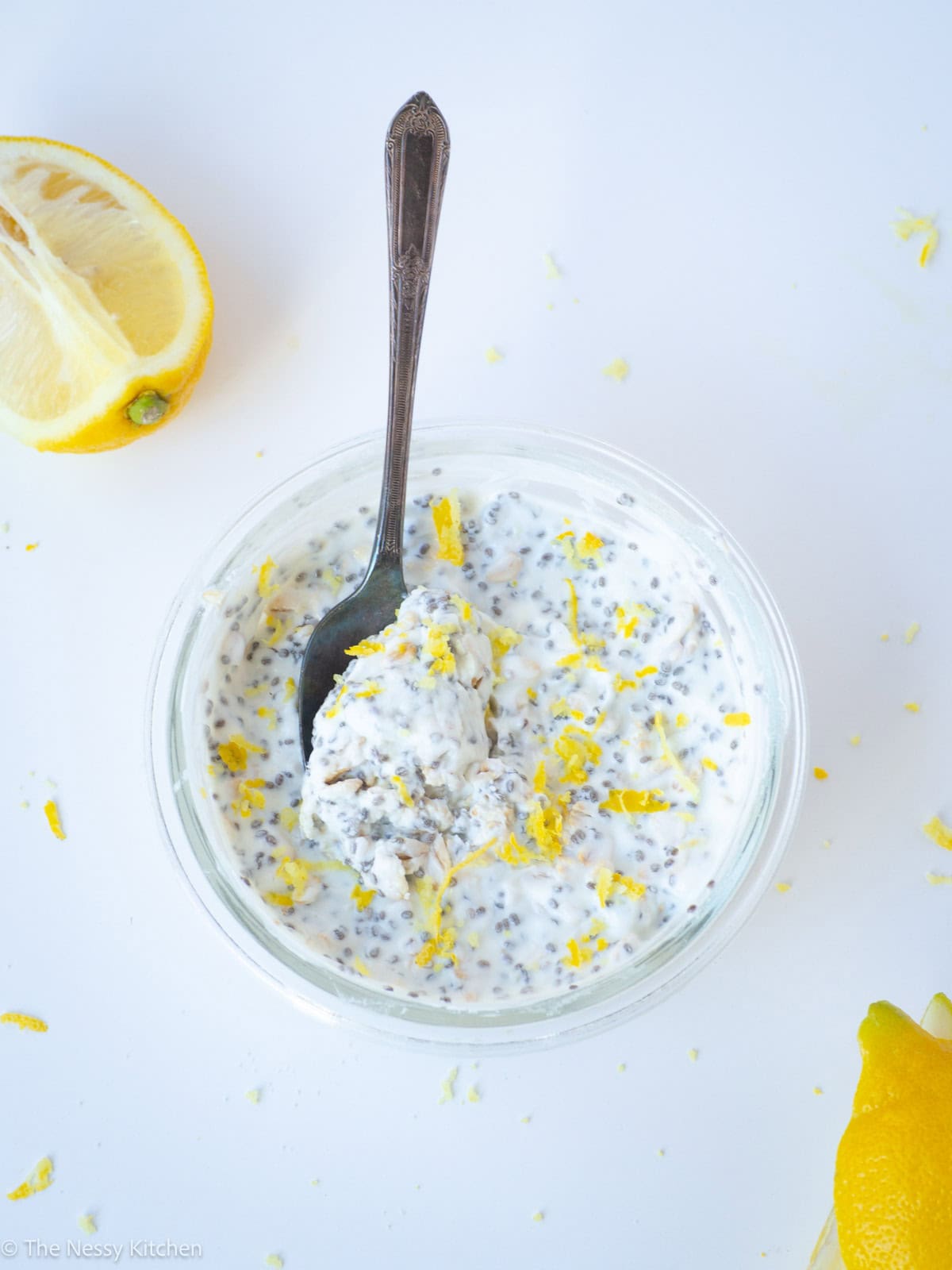 Overnight oats in a container with a spoon topped with lemon zest.