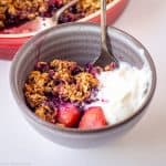 Berry crisp in a bowl with yogurt.
