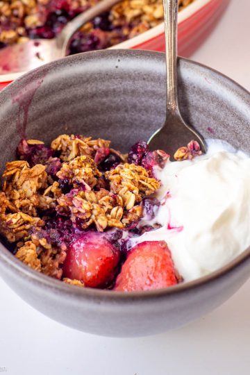 Berry crisp in a bowl with yogurt.
