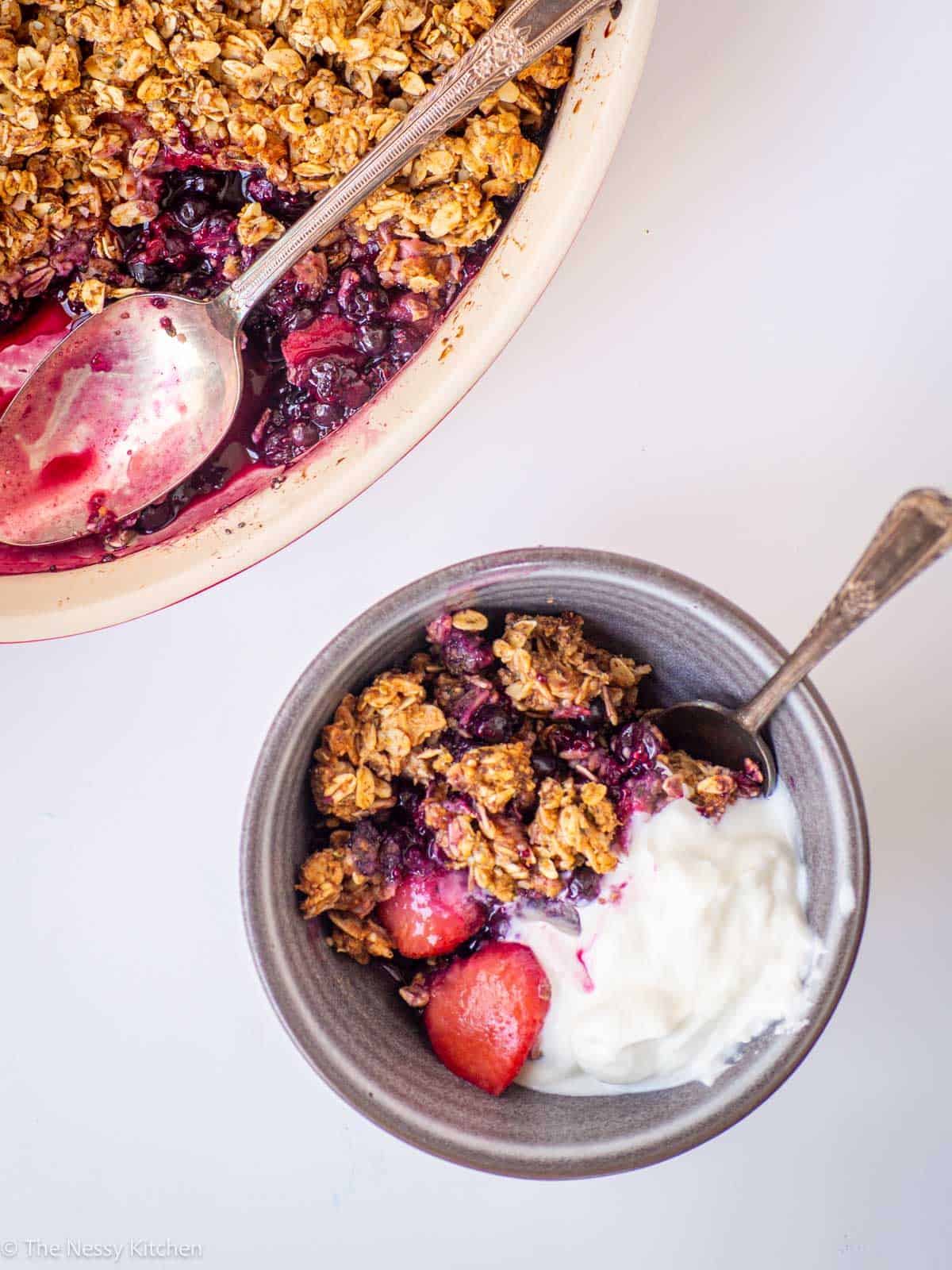 Berries in a bowl with oat topping and yogurt.
