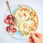 Chickpeas and parmesan on a plate with eggs and grapes.