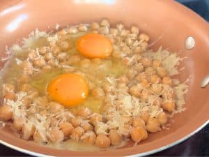 Eggs frying on top of chickpeas and parmesan.