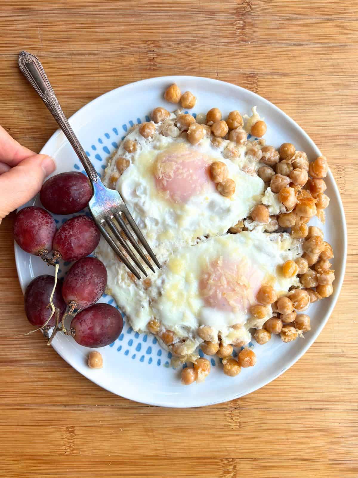 Plate of chickpea fried eggs with grapes.