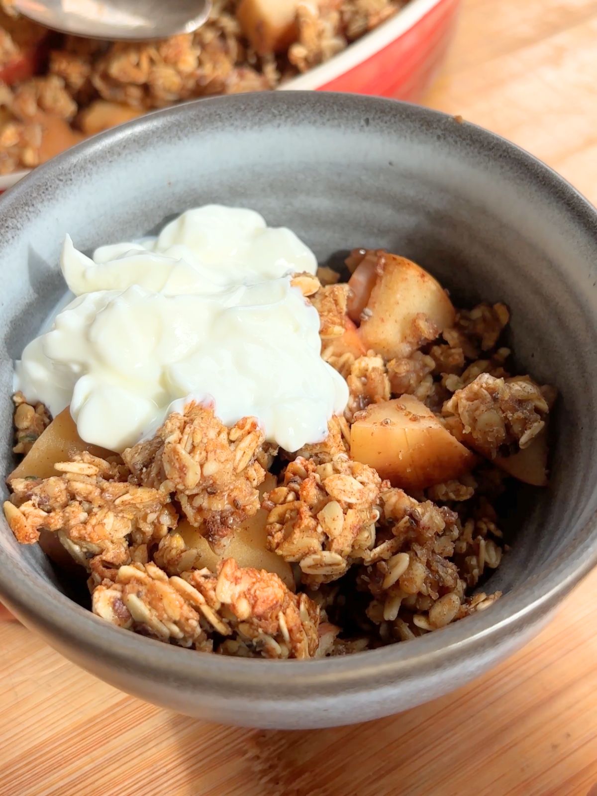 Apple crisp in a bowl topped with yogurt.