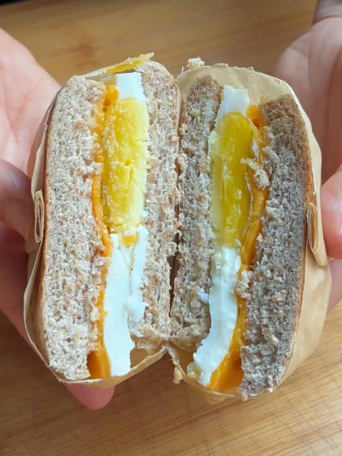 Bacon egg sandwich sliced in two.