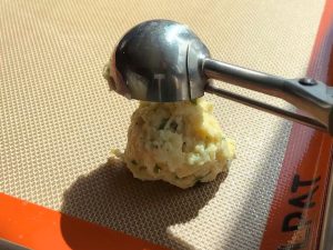 Biscuit batter being scooped onto a cookie sheet.