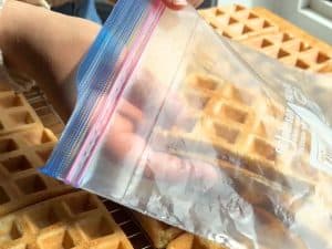Cooled waffles being placed in a ziptop bag.