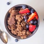 Chocolate and peanut butter granola in a bowl with mixed berries.