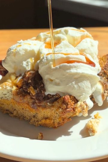 Pumpkin French toast casserole topped with whipped cream and maple syrup.